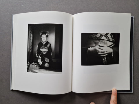 An open hardcover book displaying two black and white photographic prints on white pages
