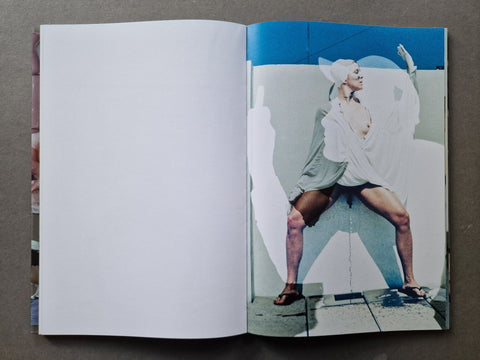 An open book, showing a printed fashion photograph on the right page of a model in a white outfit against a blue and white background.