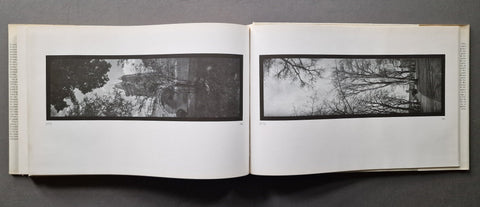 An open book showing two wide black-and-white landscape photographs side by side on white pages, photographed from above against a dark gray background.