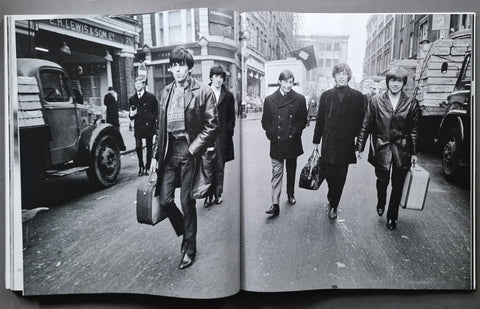 An open book showing a black-and-white printed photograph of four men walking down a city street, photographed from above on a dark surface.
