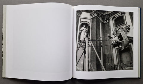 An open book showing a black-and-white architectural photograph printed on the right page, with blank white pages on the left, photographed against a dark gray background.