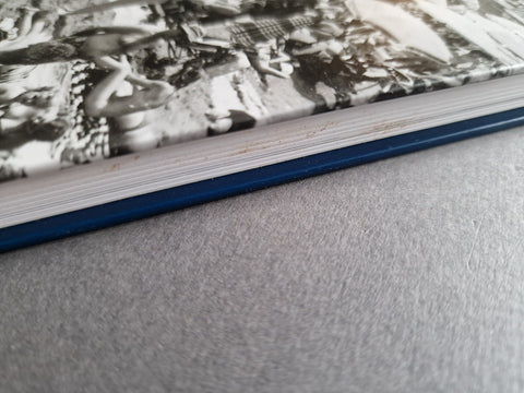 A close-up of an open book or notebook showing a black-and-white printed page, with a blue spine edge visible against a gray textured surface.