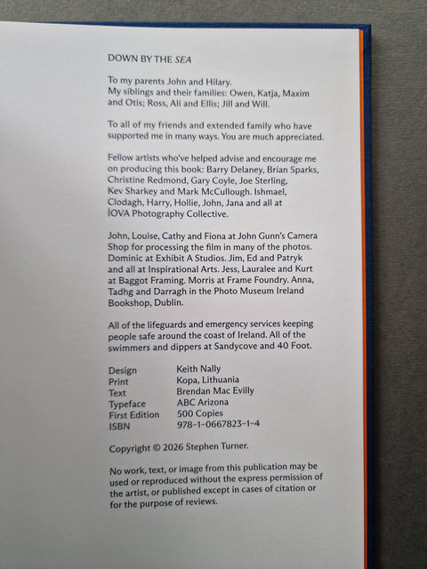 A close-up of a printed book or publication page showing a dedication and publication details, photographed against a dark background with a sliver of orange at the right edge.