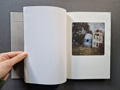 An open book spread with the left page blank and a photo of what appears to be an abandoned structure on the right