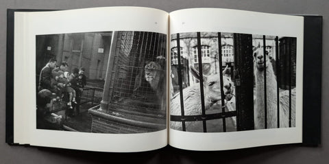 An open black-and-white art book laid flat on a dark surface, showing two printed photographs spread across the pages.