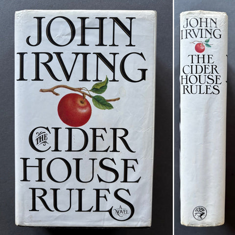 The image shows the cover and spine of a book titled 'The Cider House Rules' by John Irving, featuring a red apple on the cover and a white background.