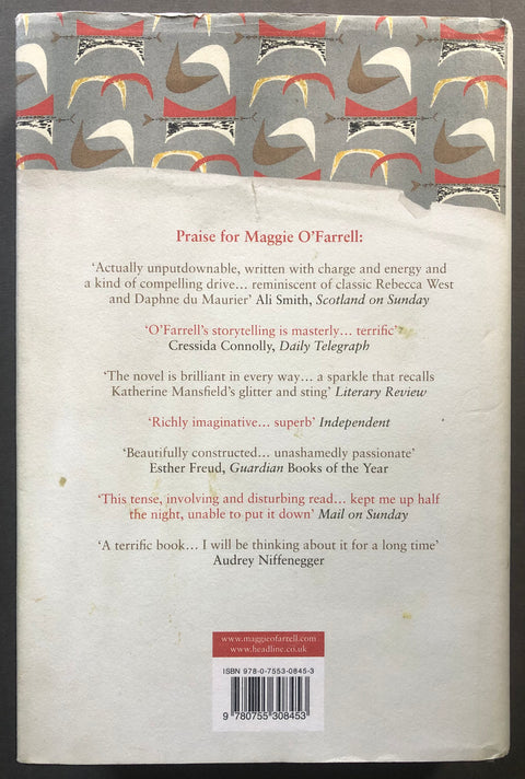 The back cover of a book featuring a cream-colored background with printed review quotes in red and black, a barcode at the bottom, and a patterned band of stylized birds at the top.