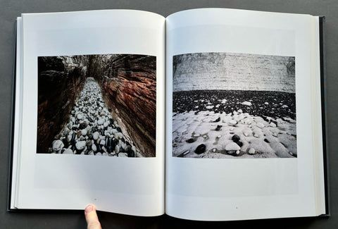 Open book showing black and white photographs of a stone wall and rocky terrain.