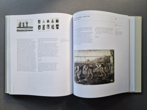 An open book spread showing printed text and black-and-white artwork on white pages, photographed from above on a dark gray surface.