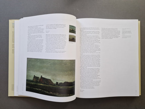 An open book spread showing printed text and a landscape photograph on the left page, photographed from above on a dark gray surface.