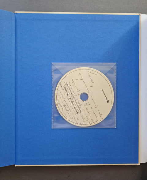 An open book or album with a bright blue cover, featuring a clear plastic sleeve holding a cream-colored printed disc in the center.