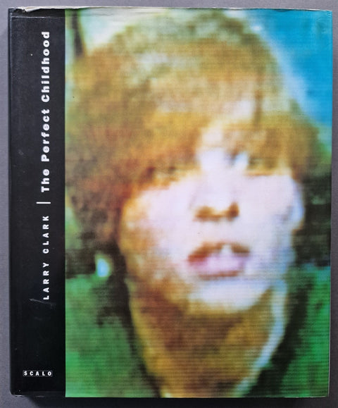 The front cover of the book 'The Perfect Childhood' by Larry Clark, published by Scal0. The cover features a grainy, low-resolution, colorful portrait of a person with blonde hair, split vertically with a black band on the left containing the title and author name in white text.