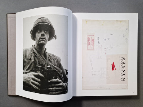 An open book, showing two printed pages. The left page contains a black-and-white portrait photograph of a soldier holding binoculars.