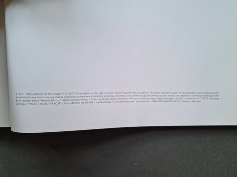 A close-up of a white printed page with small copyright and publisher text at the bottom, photographed against a dark gray surface.