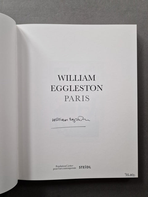 An open book or printed volume showing a white title page with the text 'WILLIAM EGGLESTON PARIS' and a handwritten signature, photographed against a dark gray background.