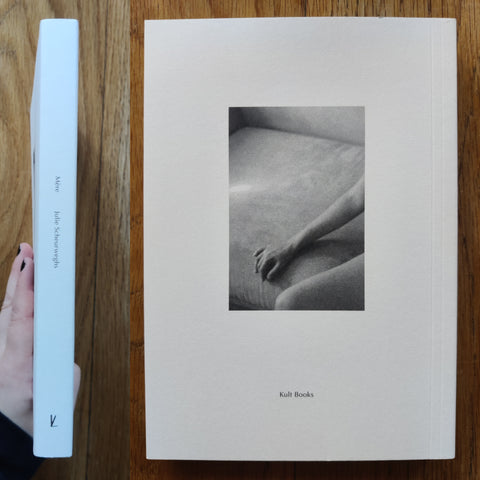 The photography boook cover of MÈRE by Julie Scheurweghs. In softcover white with a black and white close up of a face.