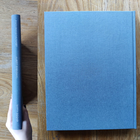 The photography book cover of A city behind the forest by Albert Grøndahl. In hardcover blue.