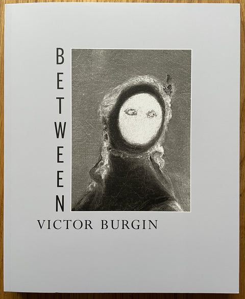 The photography book cover of Between by Victor Burgin. Paperback with image of a faceless figure on the cover.