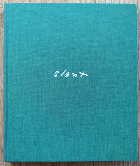 The photobook cover of Slant by Aaron Schuman. In hardcover green. Signed.