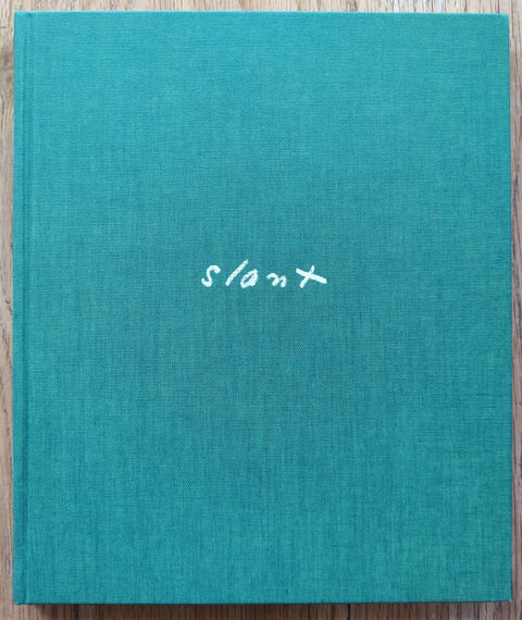 The photobook cover of Slant by Aaron Schuman. In hardcover green. Signed.