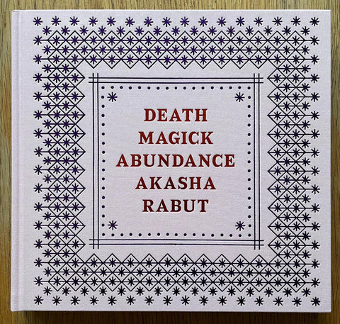 The photography book cover of Death Magick Abundance by Akasha Rabut. Hardback in light pink with stars on the cover.