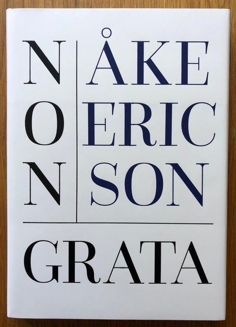 The photography book cover of Non Grata by Ake Ericson. Hardback in white with big black and blue text.