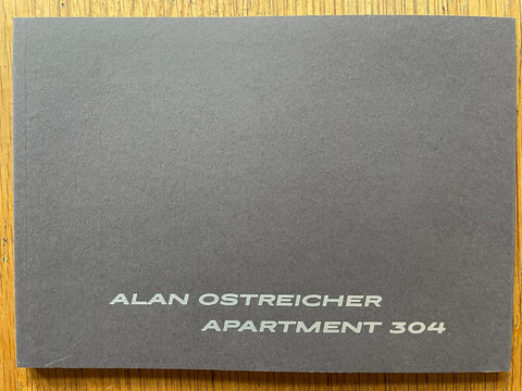 The photography book cover of Apartment 304 by Alan Ostreicher. Paperback in dark grey.