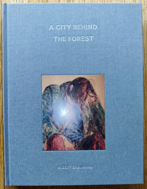 The photography book cover of A city behind the forest by Albert Grøndahl. In hardcover blue.