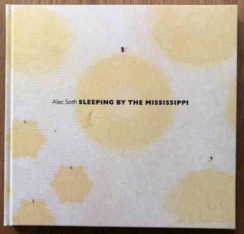 The photography book cover of Sleeping by the Mississippi by Alec Soth. Hardback white with yellow splodges.