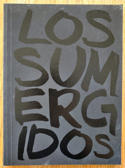The phootgraphy book cover of Los Sumergidos by Alejandro Cartagena, Juan Madrid and Carlos Loret De Mola. In softcover black.