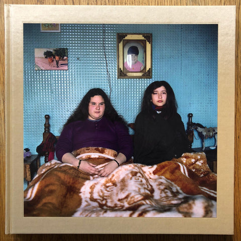 The photography book cover of The adventures of Guille and Belinda and the illusion of an everlasting summer. Hardback with beige border and photograph of two girls sat underneath a furry blanket.