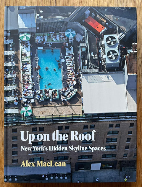 The photography book cover of Up on the Roof: New York's Hidden Skyline Spaces by Alex MacLean. Hardback with image of a rooftop pool on the cover.
