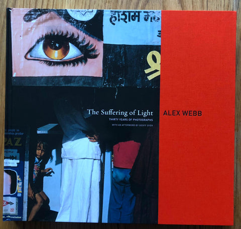 The photography book cover of The Suffering of Light: Thirty Years of Photographs by Alex Webb. Hardback with strip of red on the right.