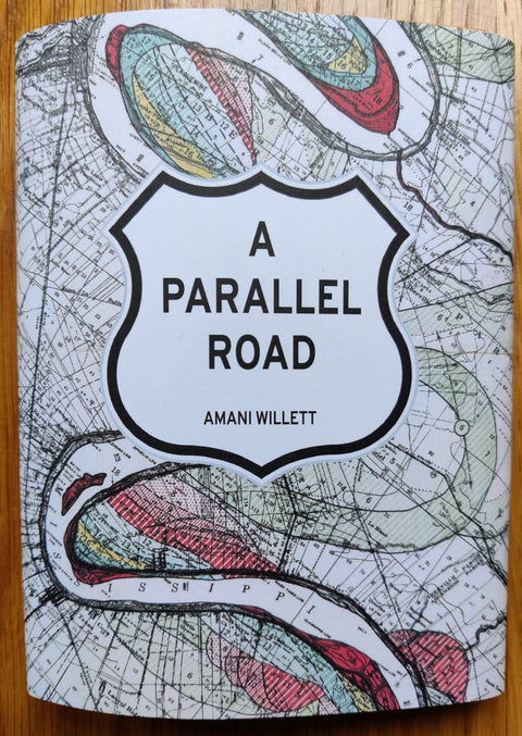 The photography book cover of A Parallel Road by Amani Willet. Paperback with map design on cover.