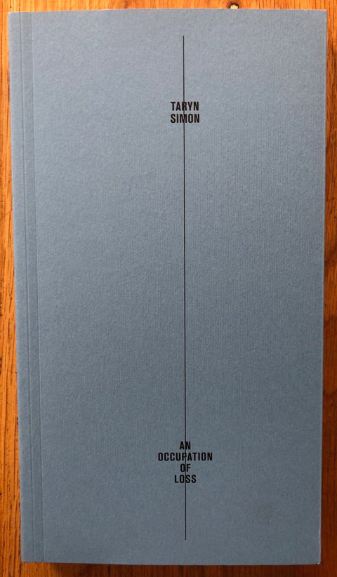 An Occupation of Loss by Taryn Simon. Paperback blue/grey cover with line down the middle of title and author.
