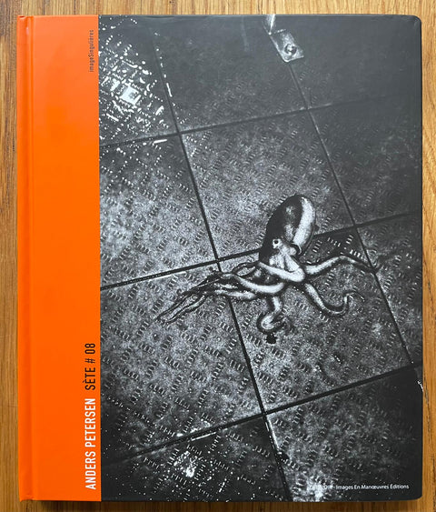 The photography book cover of Sete #08 by Anders Petersen. Hardback with B&W image of an octopus on the floor and orange binding.