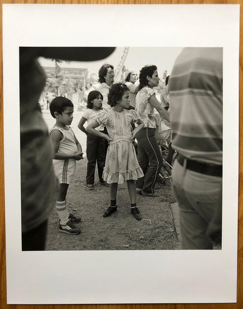 The print for Angel City West by Mark Steinmetz. B&W print of people at a fairground. Hardback yellow book, signed.