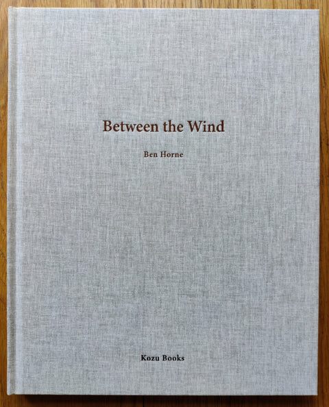 The photography book cover of Between the Wind by Ben Horne. Hardback in grey.