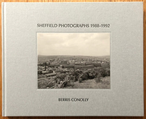 The photography book cover of Sheffield Photographs 1988-1992 by Berris Conolly. Hardback in grey with centered B&W image of Sheffield.