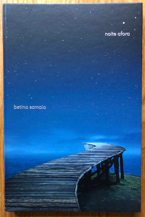 The photography book cover of Noite Afora Noite Adentro by Betina Samaia. Hardback with night sky cover.
