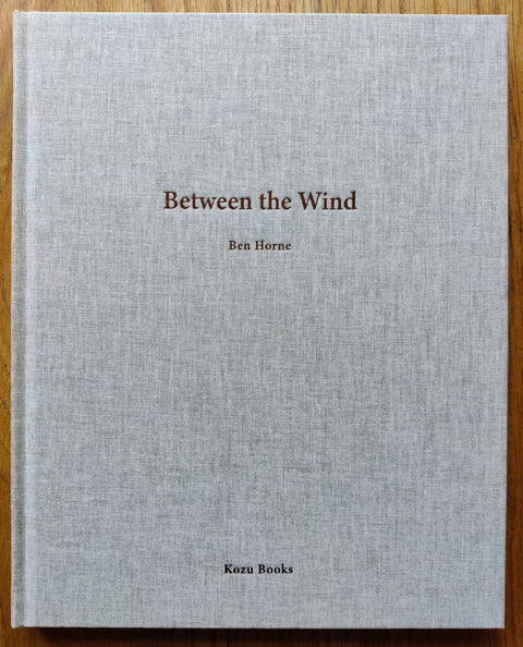 The photography book cover of Between the Wind by Ben Horne. Hardback in grey.