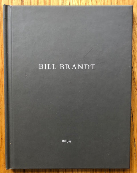 The photography book cover of Bill Brandt by Bill Jay. Hardback dark grey book.