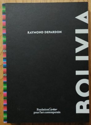 The photography book cover of Bolivia by Raymond Depardon. Hardback in black with striped colourful binding.