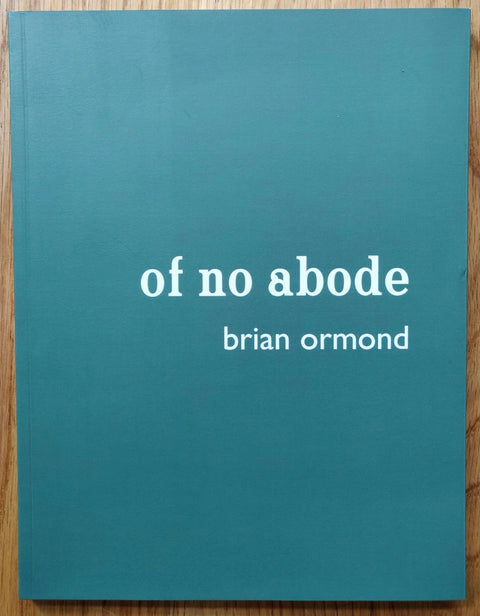 The photography book cover Of No Abode by Brian Ormond. Paperback in blue with white text.