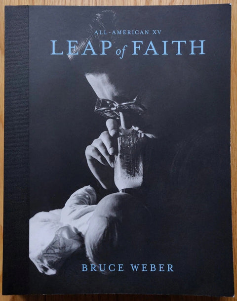 The photography book cover of Leap of Faith by Bruce Weber. Paperback black with a woman feeding a bottle to a baby on the cover.