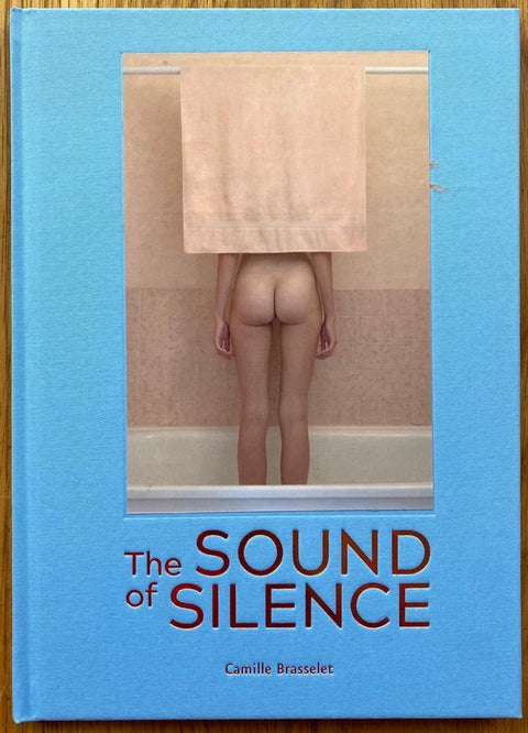 The photography book cover of The Sound of Silence by Camille Brasselet. Hardback in blue with nude image of a woman in a shower. Signed.