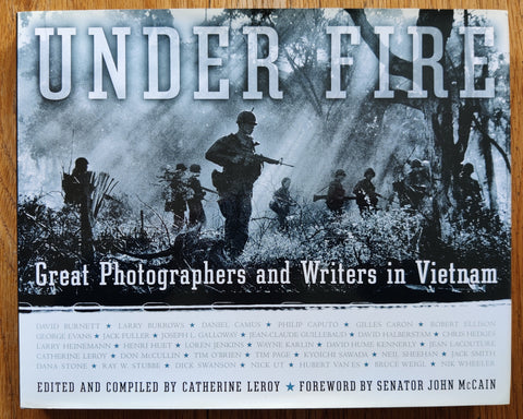The photobook cover of Under Fire: Great Photographers and Writers in Vietnam by Catherine Leroy. In duts jacketed hardcoverlight blue.
