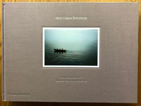 The photobook cover of Here Comes Everybody by Chris Killip. Hardback in brown with centred image of 3 people on a boat. Signed.