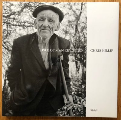 The photography book cover of Isle of Man revisited by Chris Killip. Hardback with B&W photo of an elderly man in a flat cap on the cover.