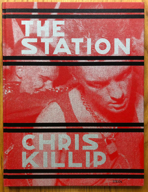 The photography book cover of The Station by Chris Killip. Hardback in red with black horizontal lines. Signed.